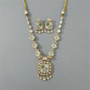 Ornate necklace and earrings set with green gemstones on a gray background