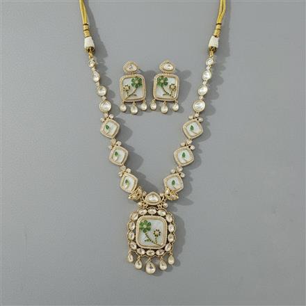 Ornate necklace and earrings set with green gemstones on a gray background